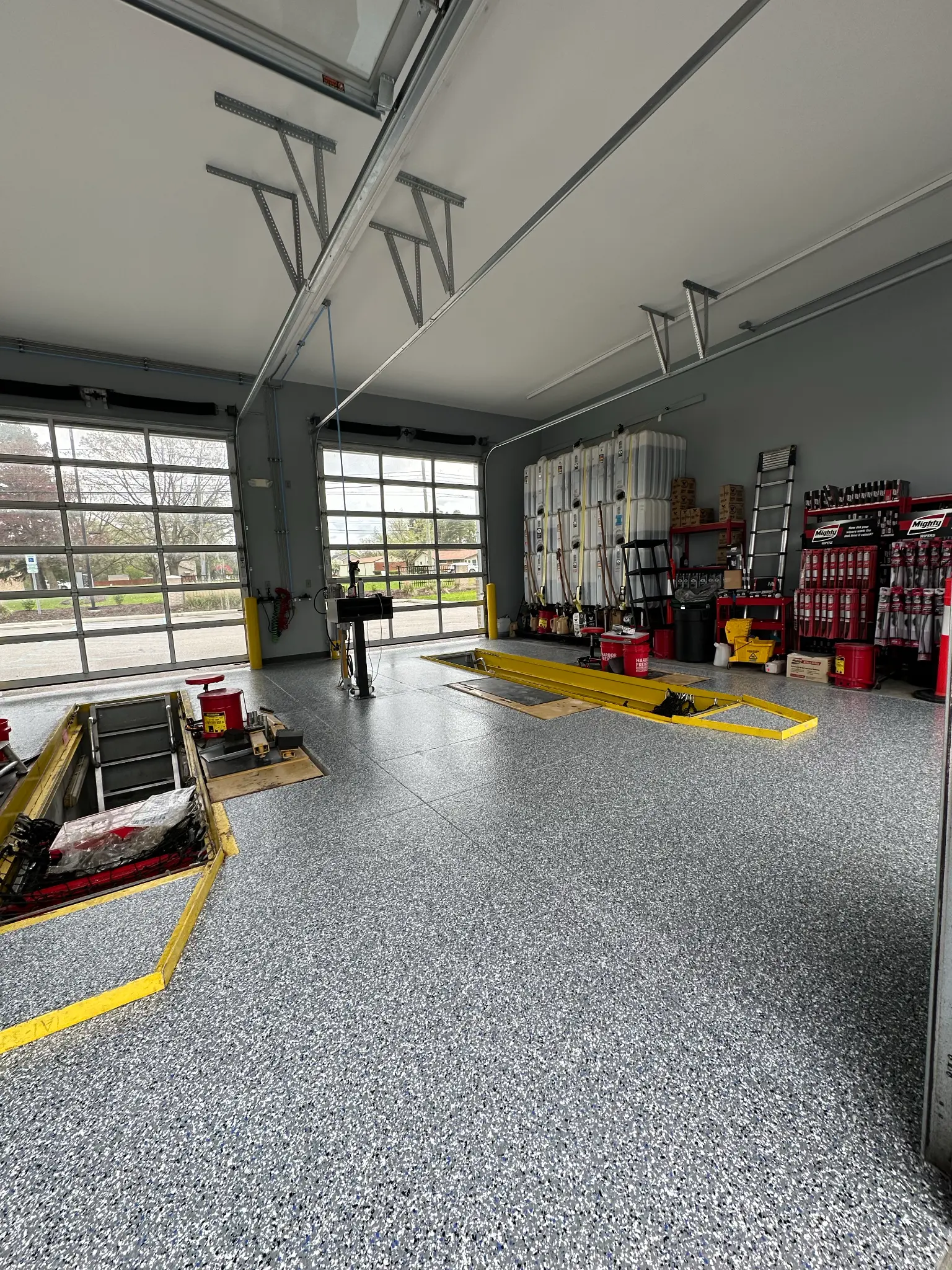 Gray decorative flake flooring with yellow safety markings in an automotive service garage