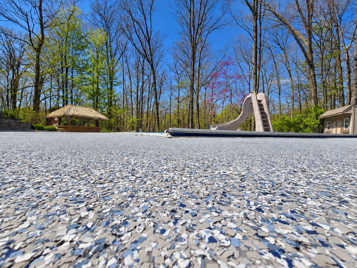 Blue, gray, and white decorative flake flooring on a poolside patio