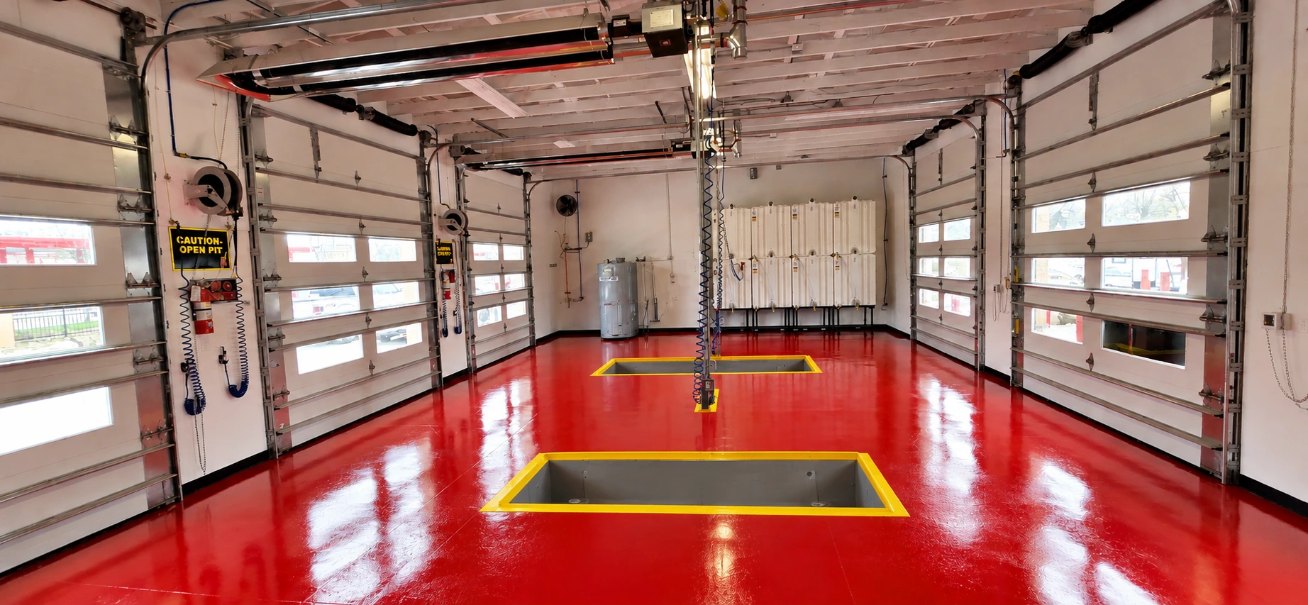 Glossy red epoxy floor with yellow safety markings in a commercial service garage